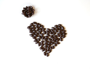 Nuts arranged in heart shape on background. Food image close up candy, chocolate milk, extra dark almond nuts. Love Texture on white grey table top view