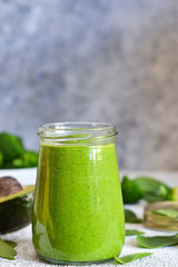 Green smoothie with spinach, avocado and broccoli on a concrete background.