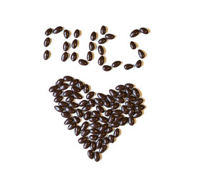 Nuts arranged in heart shape on background. Food image close up candy, chocolate milk, extra dark almond nuts. Love Texture on white grey table top view