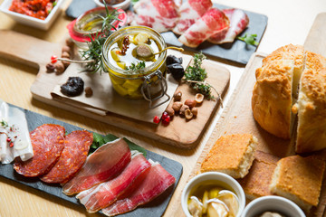 Cutting board with prosciutto, salami,bread on dark stone background.
