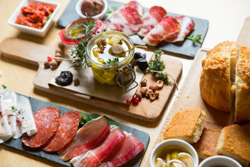 Cutting board with prosciutto, salami,bread on dark stone background.