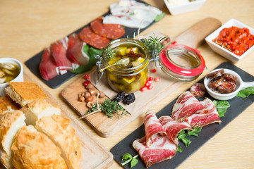 Fototapeta na wymiar Cutting board with prosciutto, salami,bread on dark stone background.
