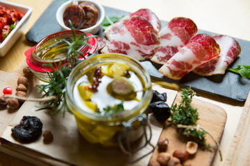 Cutting board with prosciutto, salami,bread on dark stone background.