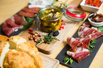 Cutting board with prosciutto, salami,bread on dark stone background.