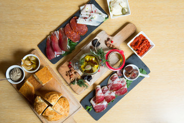 Cutting board with prosciutto, salami,bread on dark stone background.