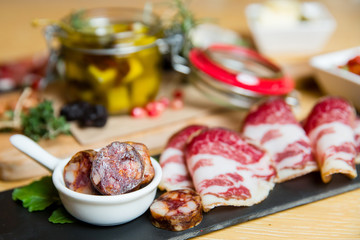 Cutting board with prosciutto, salami,bread on dark stone background.