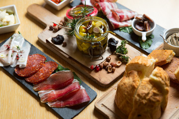 Cutting board with prosciutto, salami,bread on dark stone background.