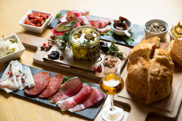 Cutting board with prosciutto, salami,bread on dark stone background.