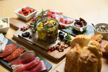 Cutting board with prosciutto, salami,bread on dark stone background.