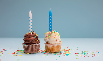 Birthday cupcakes with candles on blue pastel background, copy space.