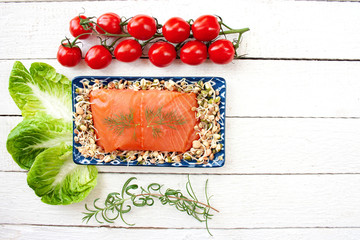 Smoked salmon on a tray filled with sprouts surrounded by sprigs of rosemary, tomatoes and lettuce © Monika