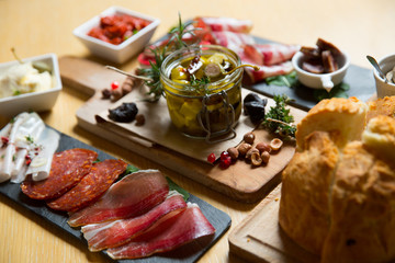 Cutting board with prosciutto, salami,bread on dark stone background.