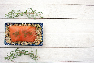 Smoked salmon on a tray filled with sprouts surrounded by rosemary branches © Monika