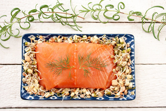 Smoked salmon on a tray filled with sprouts surrounded by rosemary branches