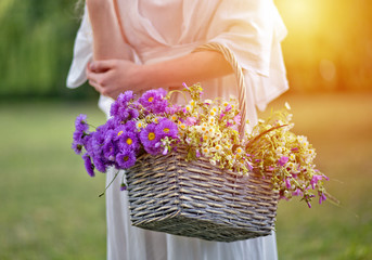 Girl with a basket of flowers. Chrysanthemums and daisies in a basket.