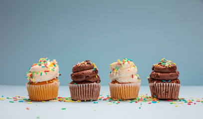 Cupcakes with colorful sprinkles on blue pastel background, copy space.