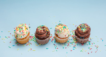 Cupcakes with colorful sprinkles on blue pastel background, copy space.