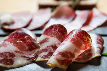 Cutting board with prosciutto, salami,bread on dark stone background.