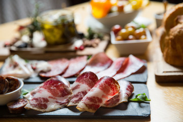 Cutting board with prosciutto, salami,bread on dark stone background.