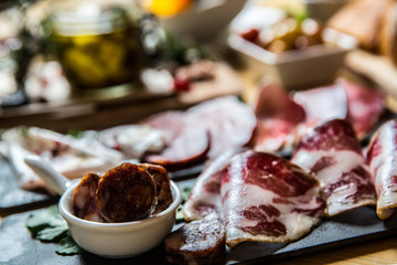 Cutting board with prosciutto, salami,bread on dark stone background.