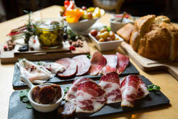 Cutting board with prosciutto, salami,bread on dark stone background.
