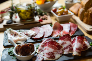 Cutting board with prosciutto, salami,bread on dark stone background.