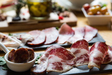Cutting board with prosciutto, salami,bread on dark stone background.