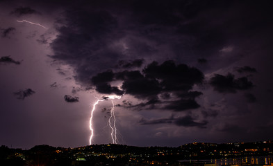 Bacoli, Italy. A sudden storm arrives and illuminates the city with the Fusaro lake in the foreground.