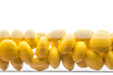 Medicine yellow pills or tablets drop in the brown glass bottle on white background. Isolate on a white background