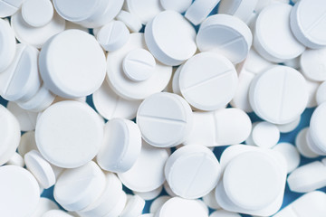 White pills or capsules on a blue background with copy space.