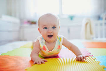baby girl lying on colorful play mat on the floor