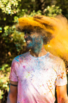 Man shaking his head, full of colorful powder paint, celebrating Holi, Festival of Colors
