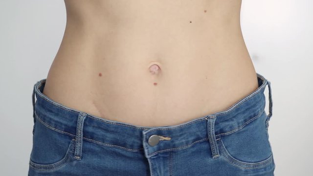 slim girl in too big jeans showing her belly