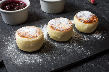 Cottage cheese pancakes on stone background. Syrniki with sour cream. Homemade food