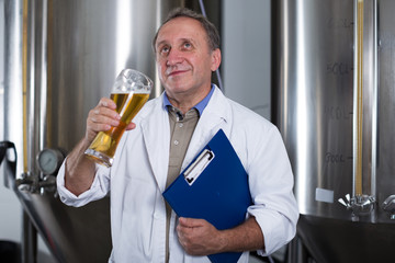 Man expert with folder is analizying the quality of beer in flask