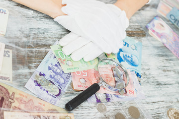 Hands in the white gloves hold different banknotes
