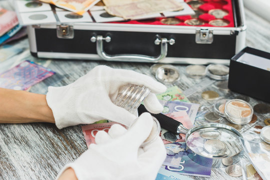 Hands in the white gloves hold different banknotes