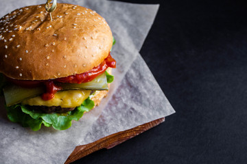 fresh tasty cheese burger with french fries and vegetables on black background