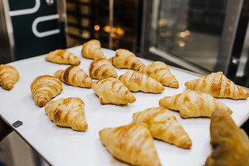 .Working woman using the bakery oven to bake the croissant of the day. Bakery concept. Lifestyle..