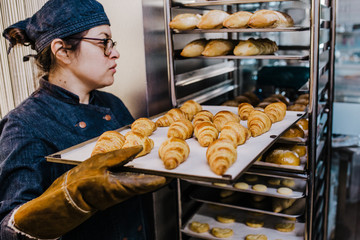 .Working woman using the bakery oven to bake the croissant of the day. Bakery concept. Lifestyle..