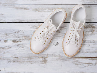 Womens shoes (white sneakers) on  wooden background. Spring summer collection. Fashion concept. Flat lay