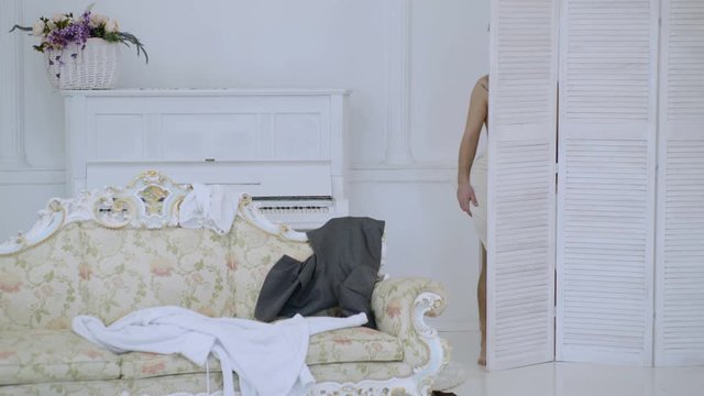 Man, lover in white interior caught naked. Exposing lovers concept. Hipster naked on shocked face unexpectedly detected in bedroom. Man with beard and mustache hiding behind folding screen.