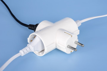 Tree plugs socketed into white electric splitter on a blue background. Splitter for simultaneous...