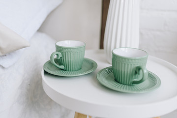 Fototapeta na wymiar Two cups with saucers on a modern nightstand or bedside table. Coffee cups.