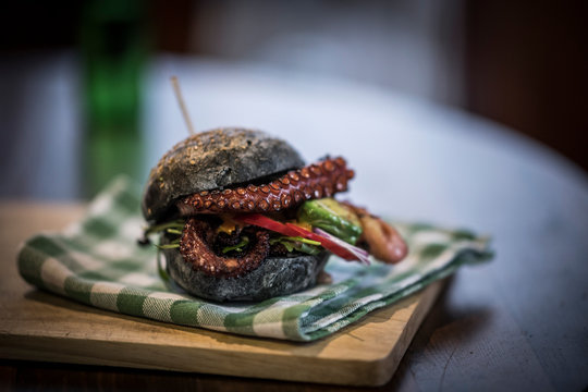 Black burger with fried octopus and vegetables