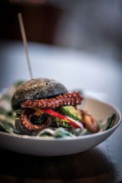 Black burger with fried octopus and vegetables