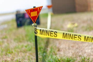 land mine warning sign stands on grass