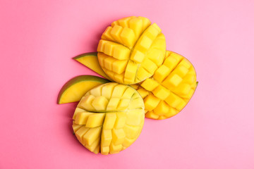 Cut tropical ripe mango on color background, top view