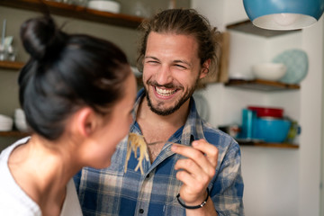 Young couple preparing food together, tasting spaghetti