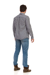 Fototapeta premium Young Man In Boots, Jeans And Lumberjack Shirt Is Standing. Rear View.